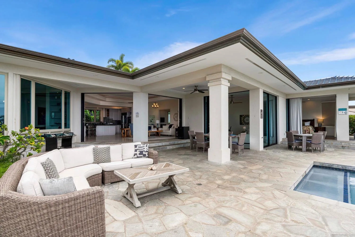 A spacious outdoor patio with seating and a pool beside a modern house.