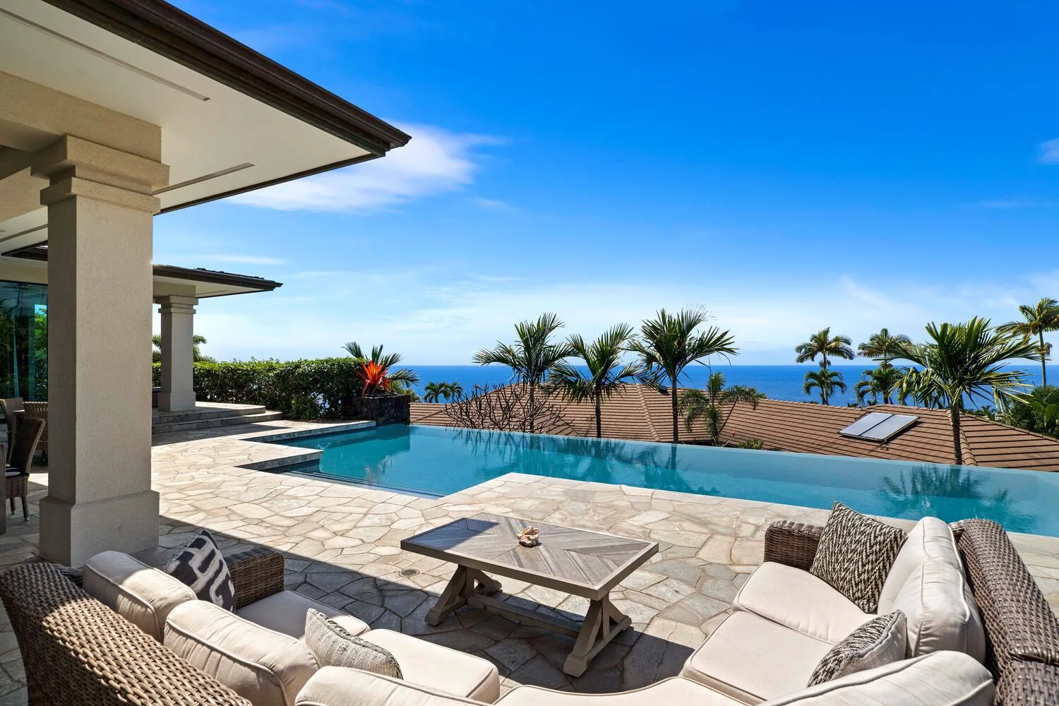 A patio with a swimming pool, outdoor seating, and ocean views.