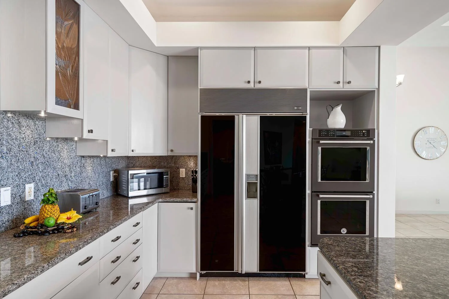 A bright kitchen with white cabinets, dark countertops, and built-in appliances.