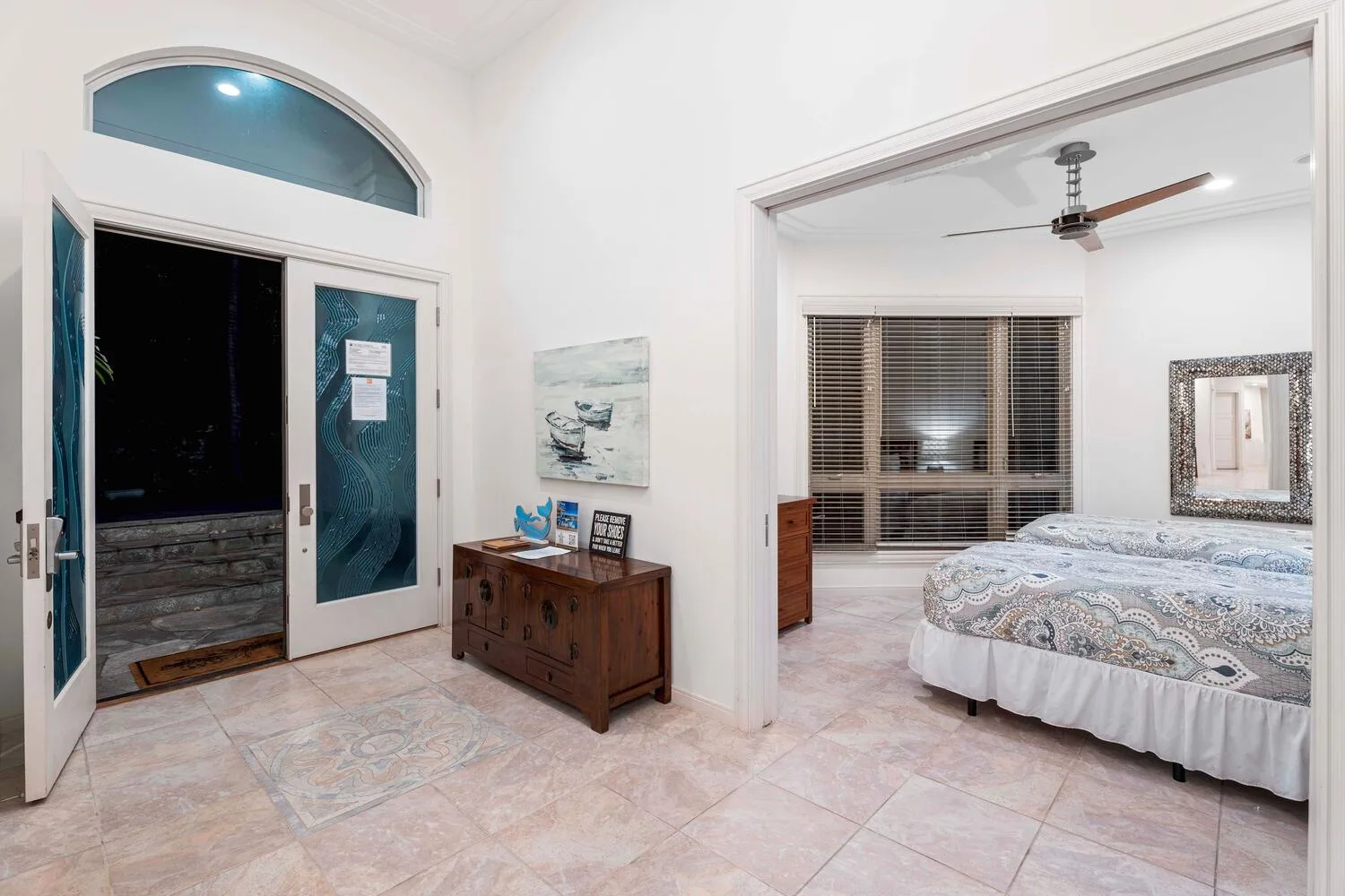A bedroom is visible through a wide doorway beside an open entrance.