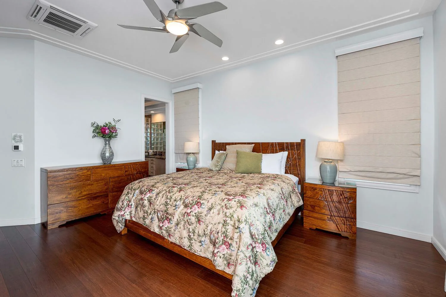 A bedroom with a wooden bed, floral bedding, and matching bedside tables.