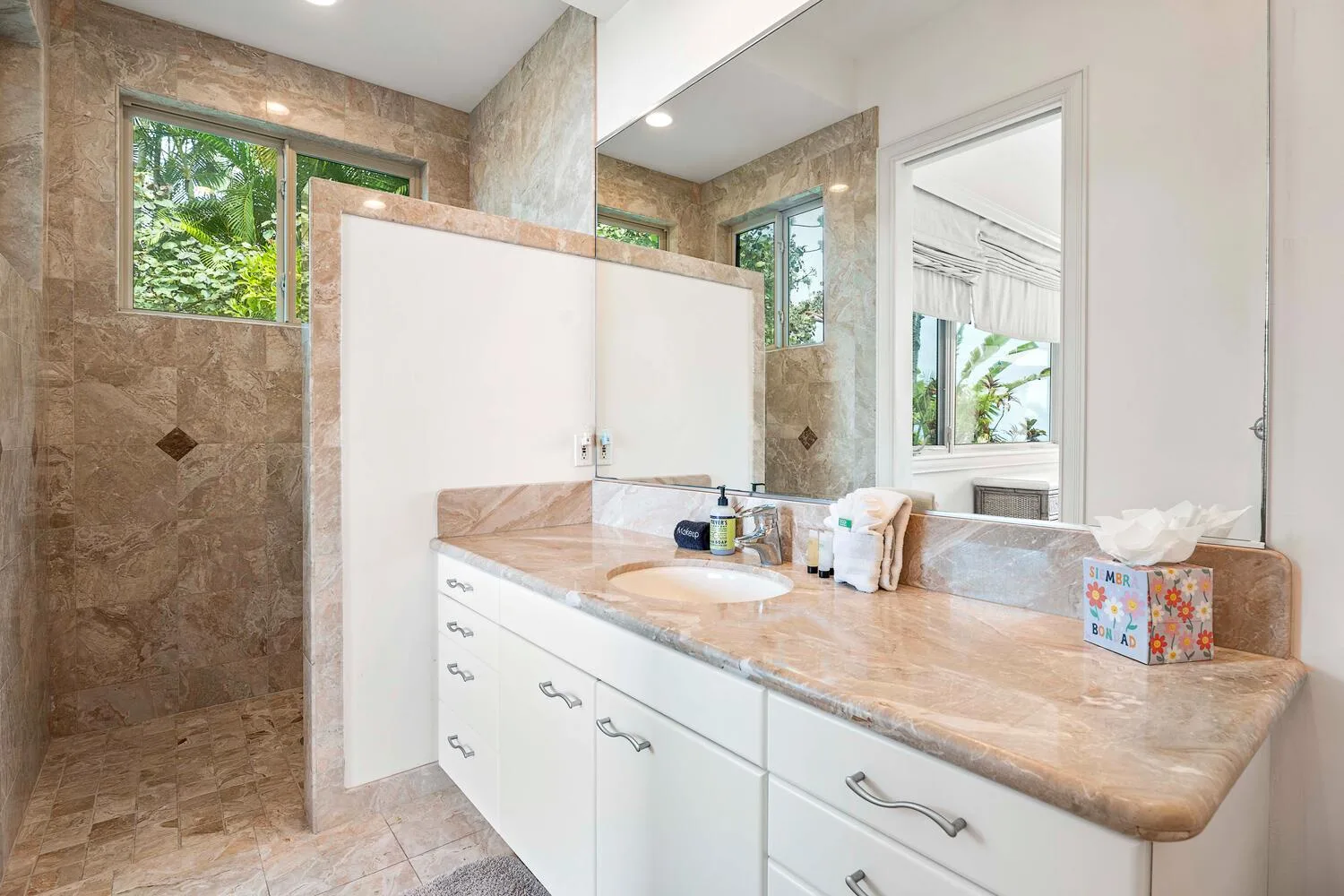 A bathroom vanity with a sink sits beside a tiled shower area.