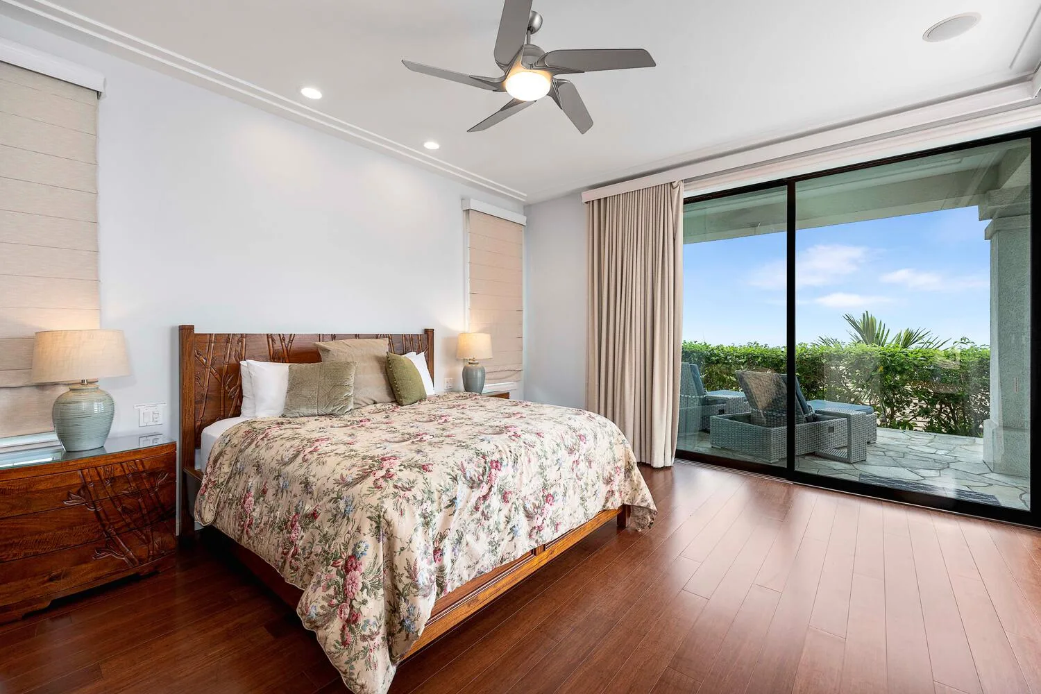 A bedroom with a floral bedspread and sliding glass doors opening onto a patio.