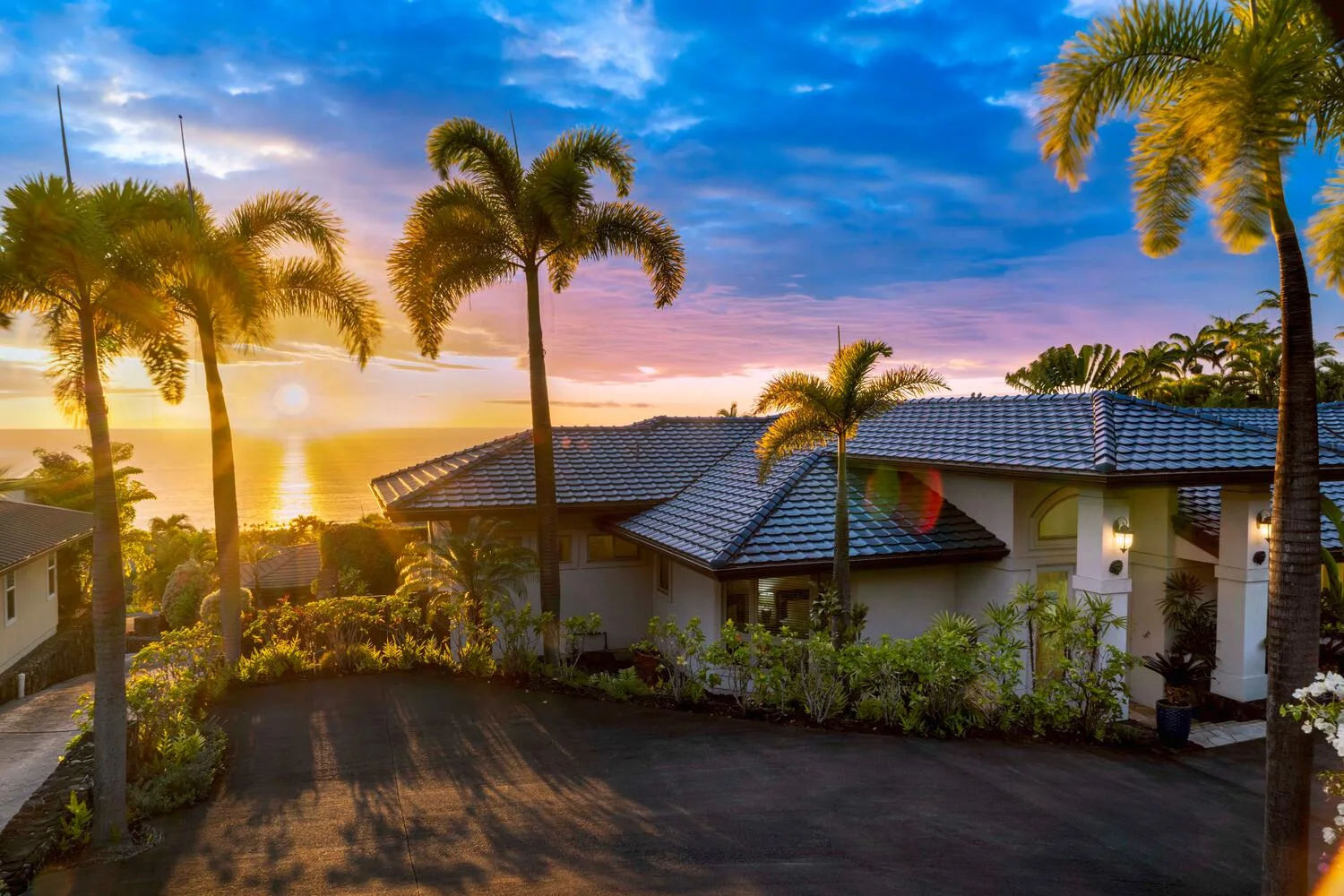 A house with a tiled roof and palm trees at sunset.