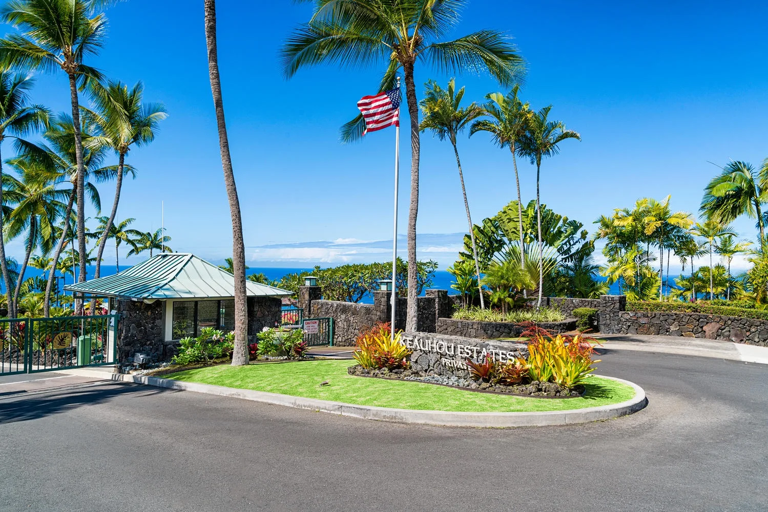 A tropical entrance road curves past landscaped grounds and palm trees.