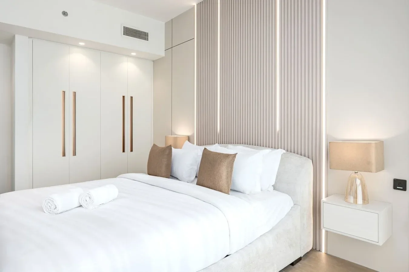Un dormitorio luminoso con una cama bien tendida y una lámpara de noche.