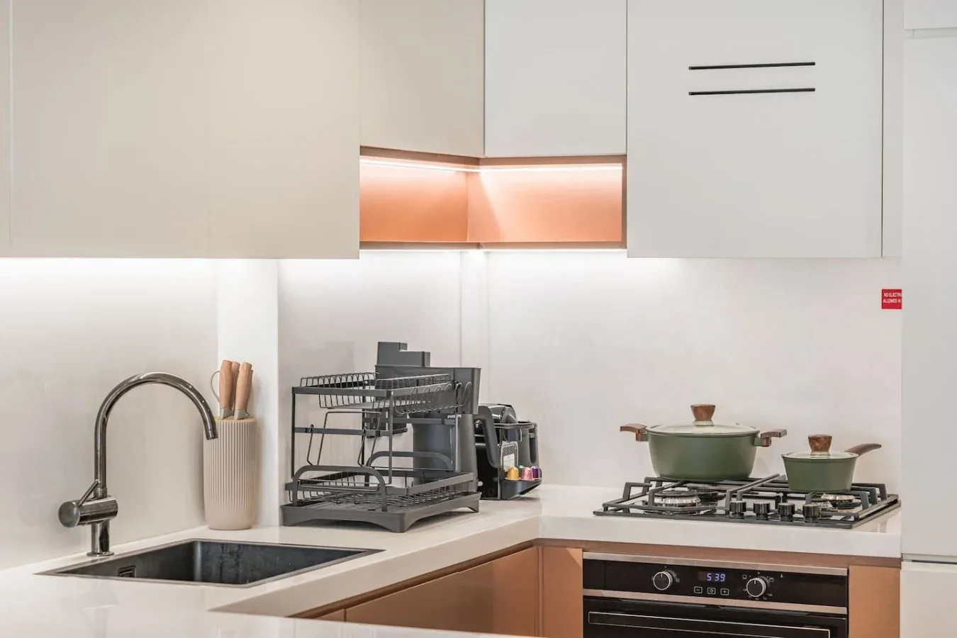Una cocina moderna con gabinetes claros, fregadero y cocina de gas.