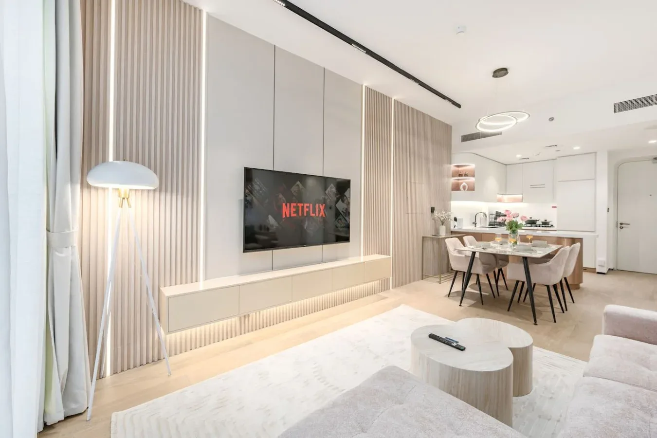 Una luminosa sala-comedor de concepto abierto con televisor en la pared y mesa de comedor.