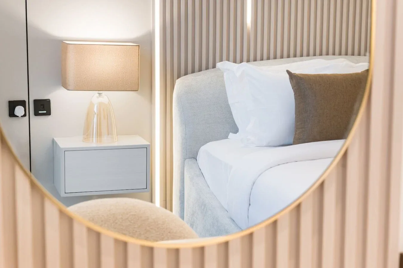 Un dormitorio con una cama arreglada y una lámpara de noche.