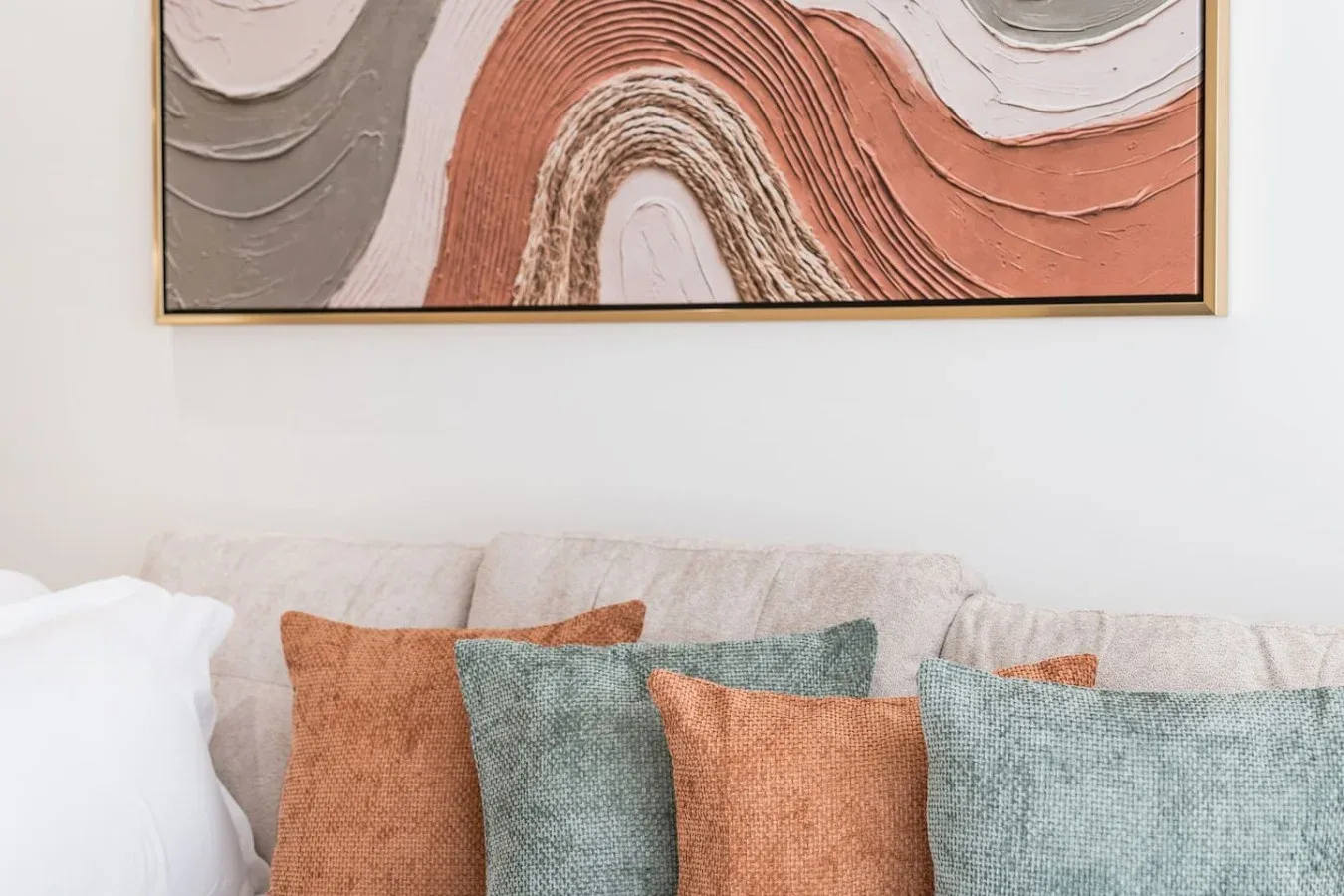 Una zona de estar con cojines de colores bajo una pintura abstracta.