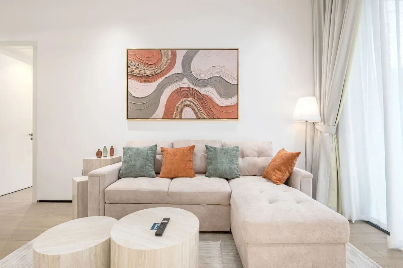 Una sala luminosa con asientos seccionales, mesas redondas y arte abstracto en la pared.