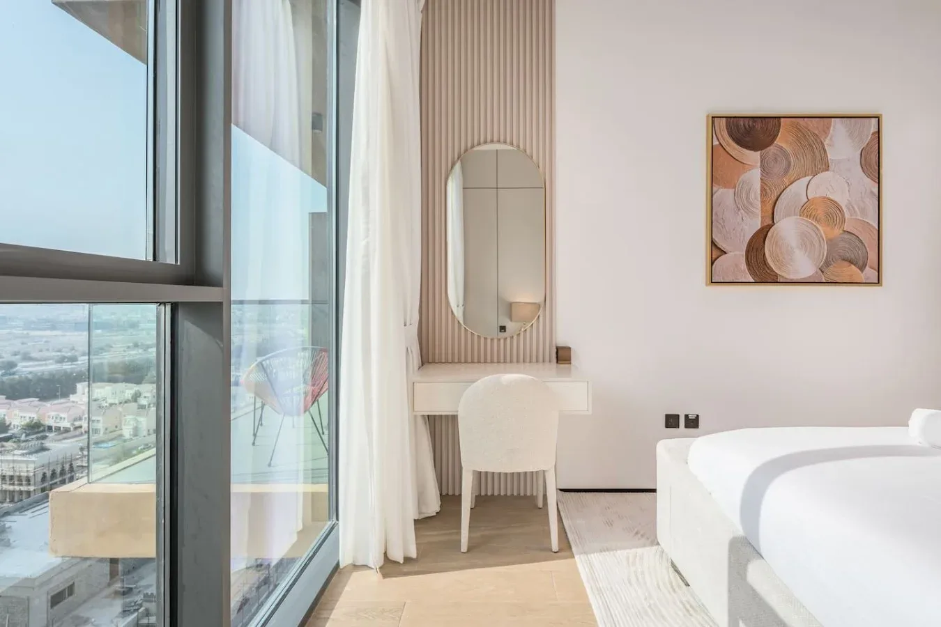 Un dormitorio luminoso con una cama, un escritorio y ventanas de suelo a techo.