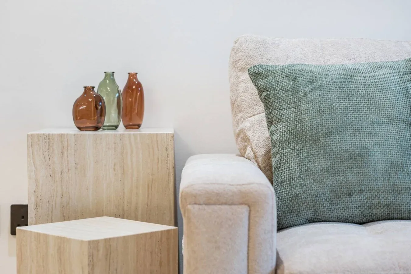 Una zona de asientos con un cojín verde texturizado junto a una mesa de madera clara.