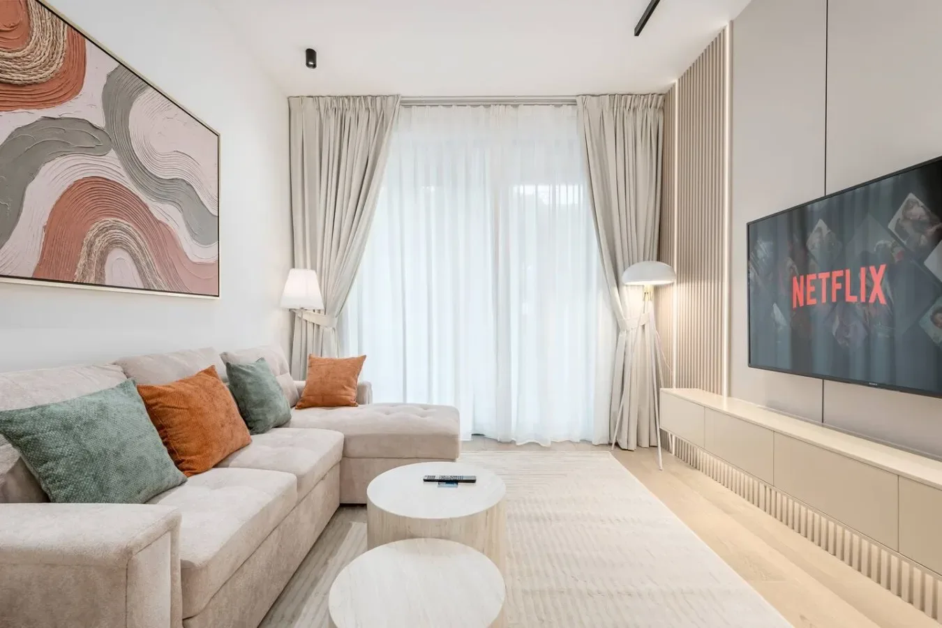 Una sala luminosa con una zona de asientos y una gran ventana con cortinas.