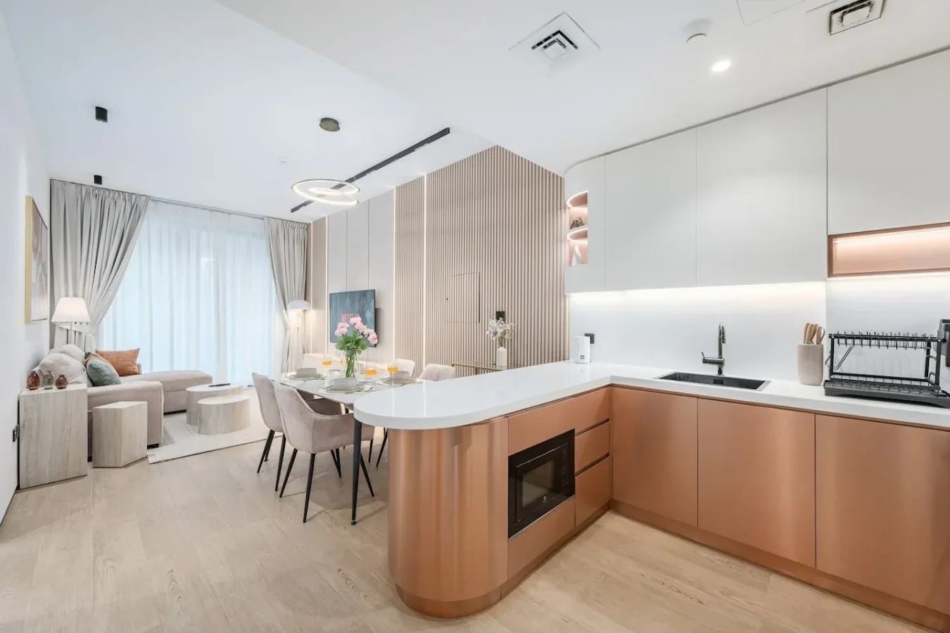 Cocina y comedor de concepto abierto, con una isla curva y asientos junto a las ventanas.