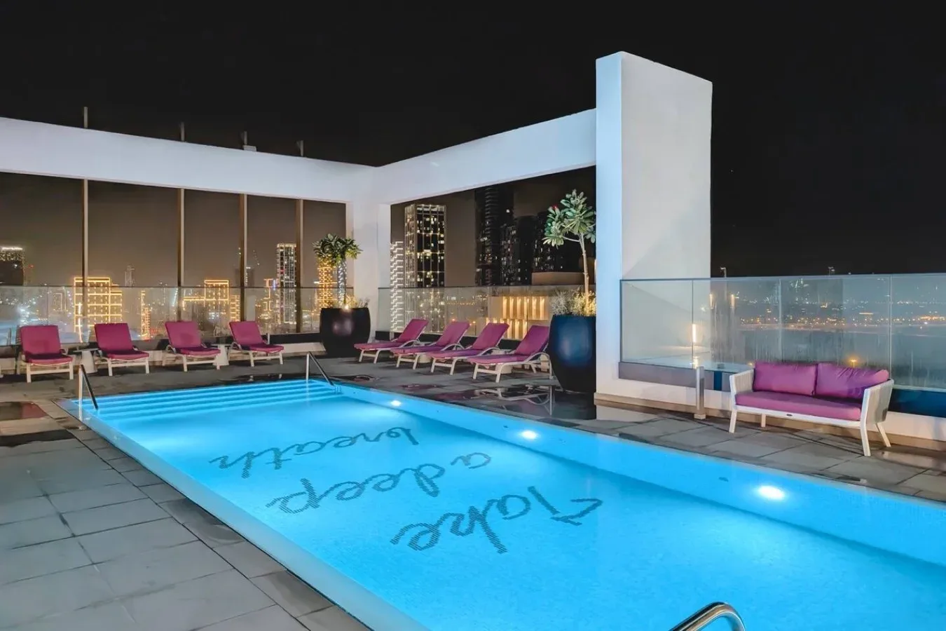 Una piscina en la azotea está rodeada de asientos y vistas de la ciudad.