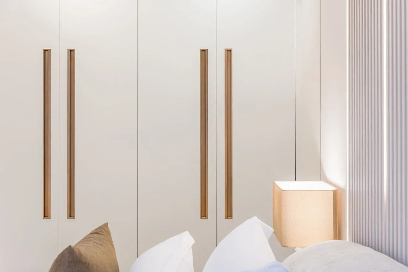 Dormitorio con una cama debajo de armarios altos empotrados.