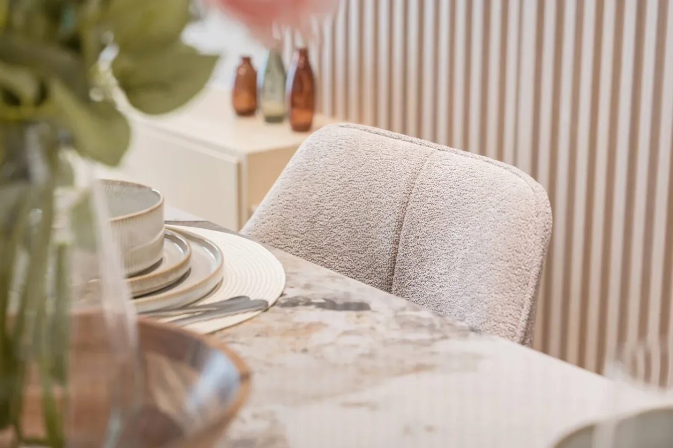 Comedor con una mesa puesta y asientos tapizados.