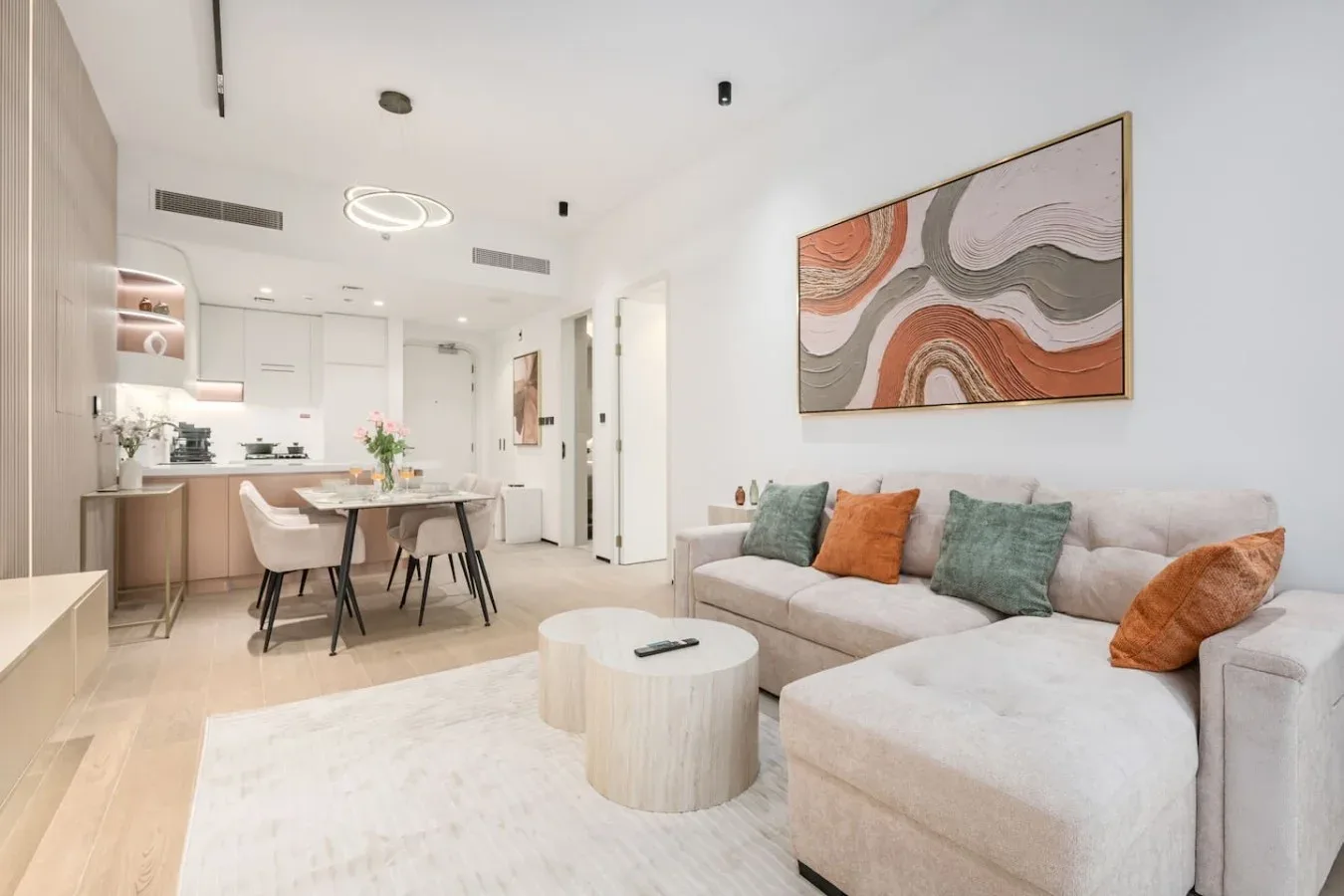 Una luminosa sala de estar y cocina de concepto abierto, con sofá seccional y mesa de comedor.