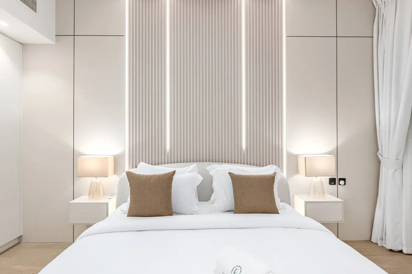 Un dormitorio luminoso con una cama bien tendida y lámparas a ambos lados.