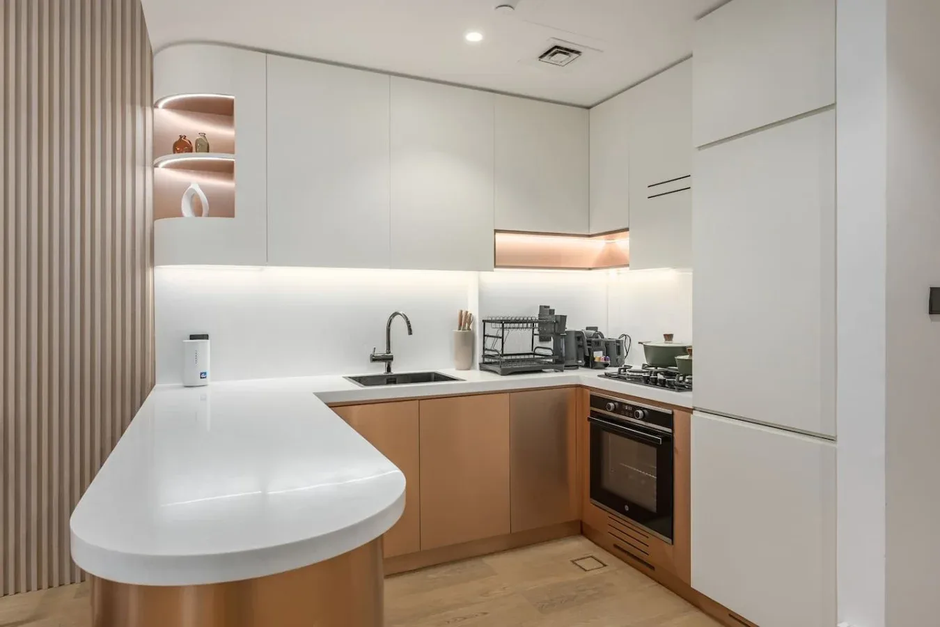Una cocina moderna con encimeras blancas y gabinetes en tono madera.