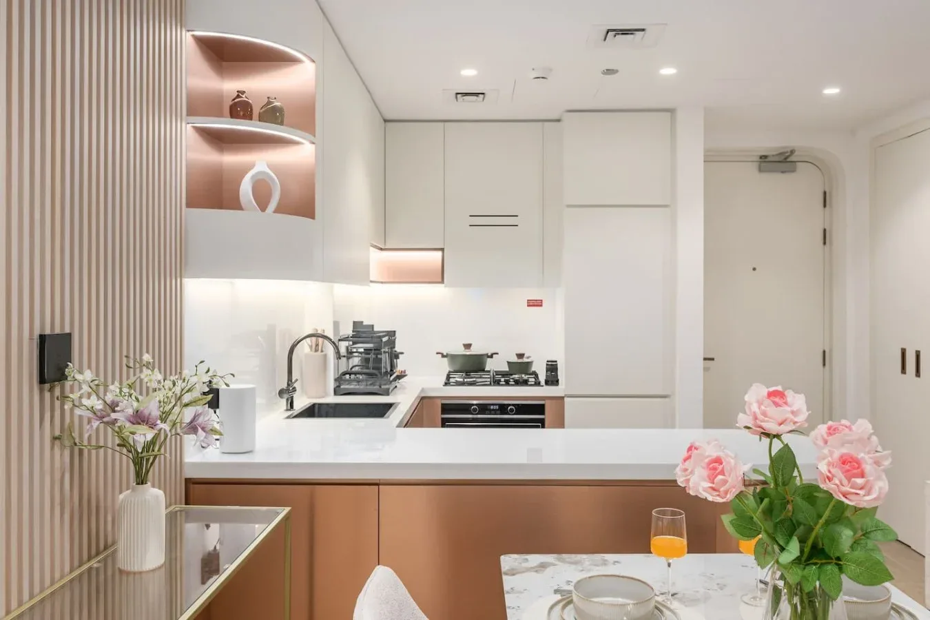 Una cocina moderna y luminosa con una isla blanca y gabinetes rosados.