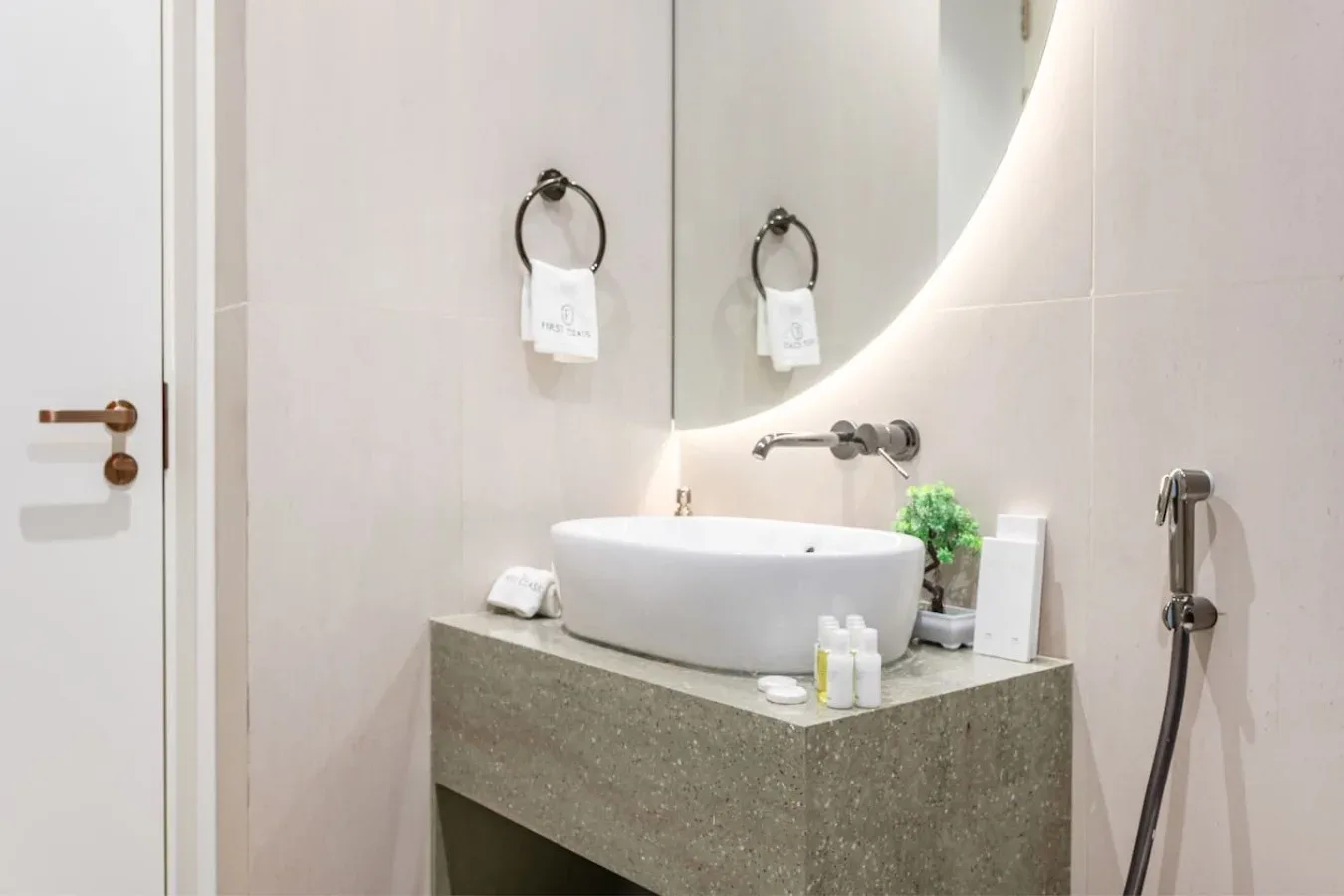Un tocador de baño con un lavabo blanco y un espejo grande iluminado.
