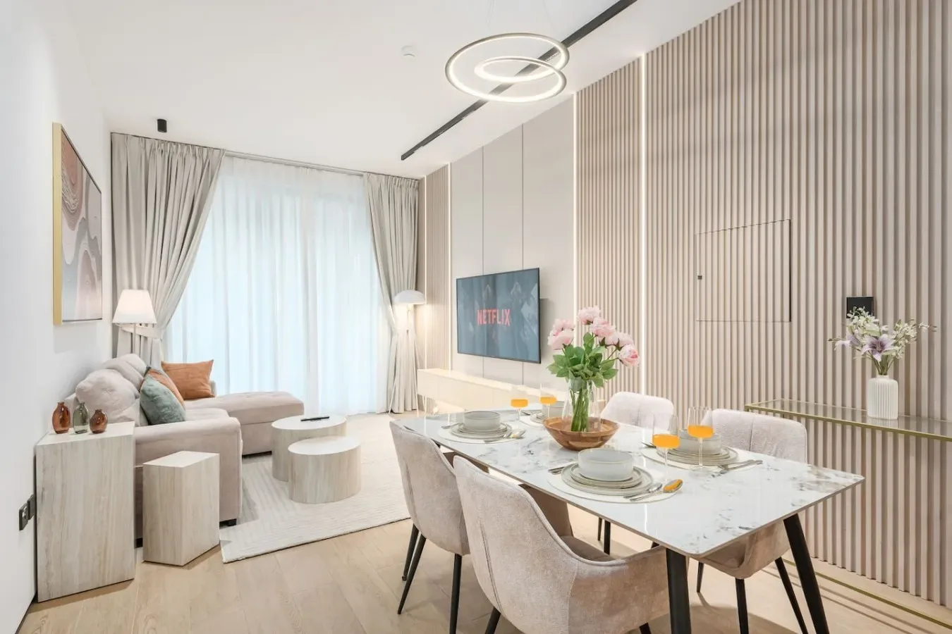 Una luminosa sala de estar y comedor con una mesa junto a una ventana con cortinas.