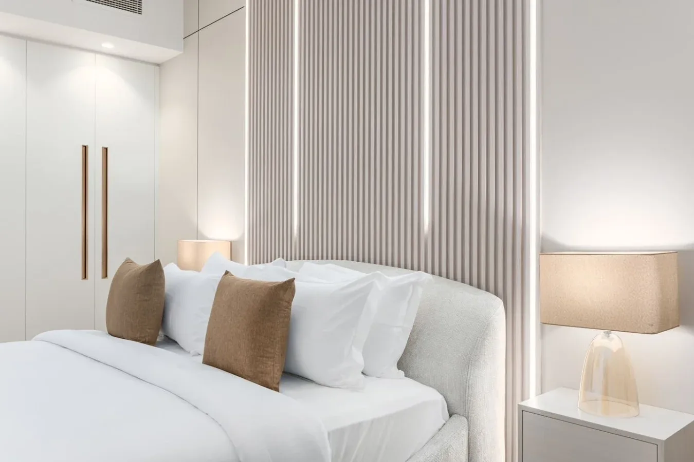 Una cama bien hecha con ropa de cama blanca y cojines decorativos marrones.