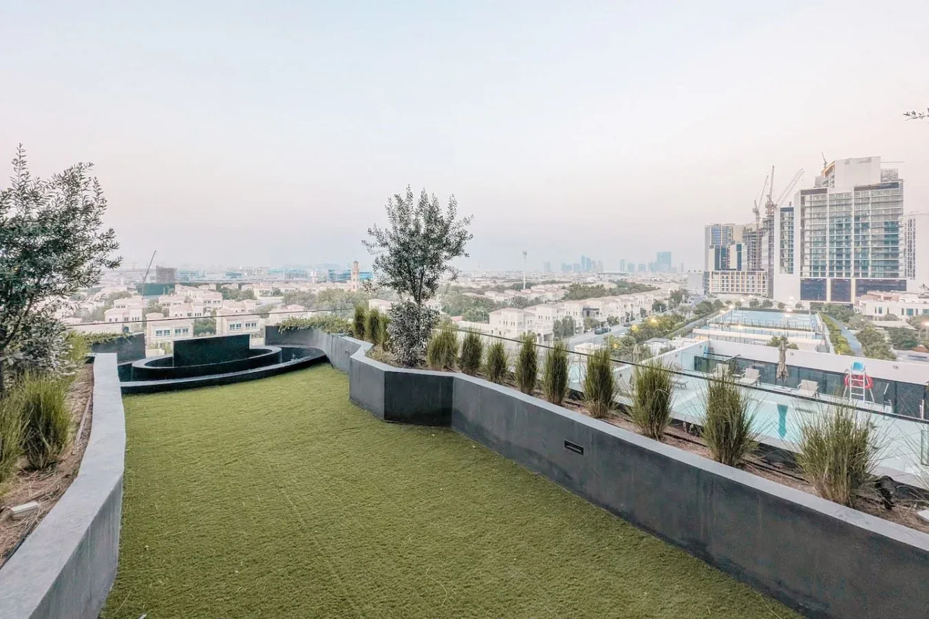 Una terraza en la azotea con suelo verde y vistas a edificios cercanos.