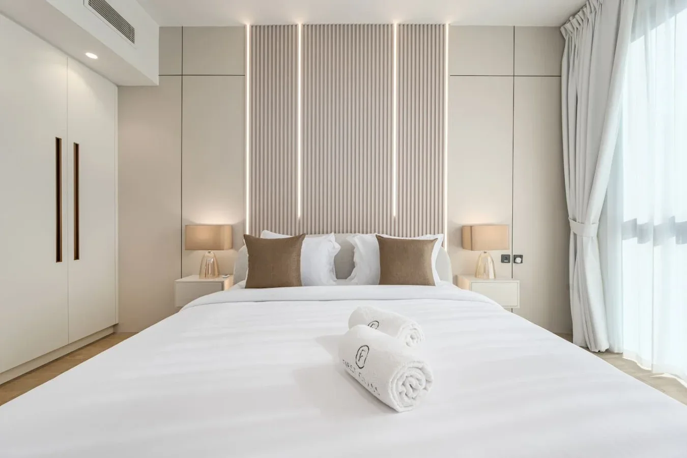 Un dormitorio luminoso con una cama bien tendida y cortinas largas.
