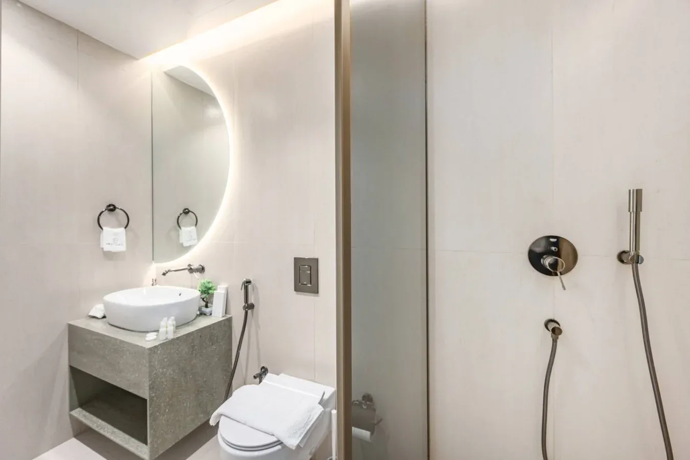 Un baño con lavabo, inodoro y accesorios de ducha en la pared.