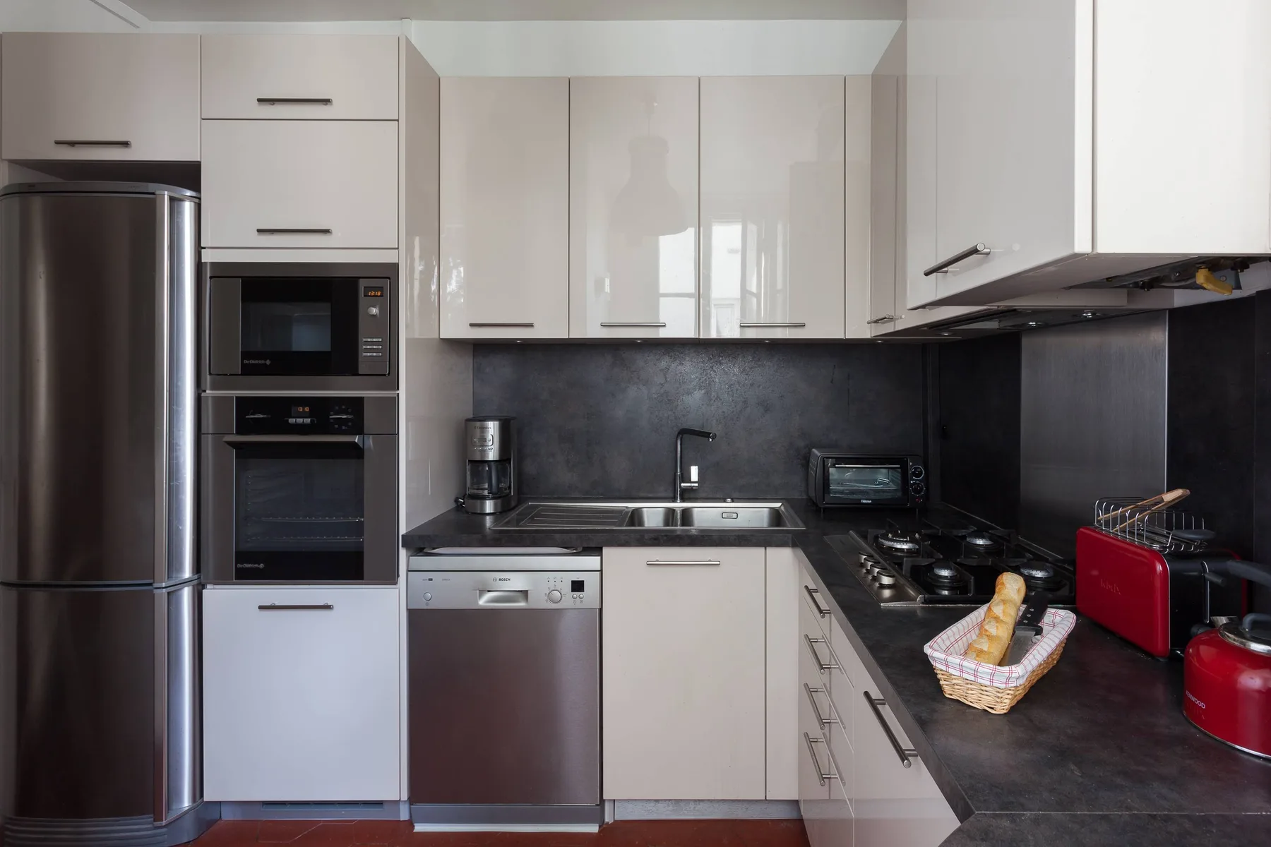 A modern kitchen with white cabinets, dark countertops, and stainless-steel appliances.