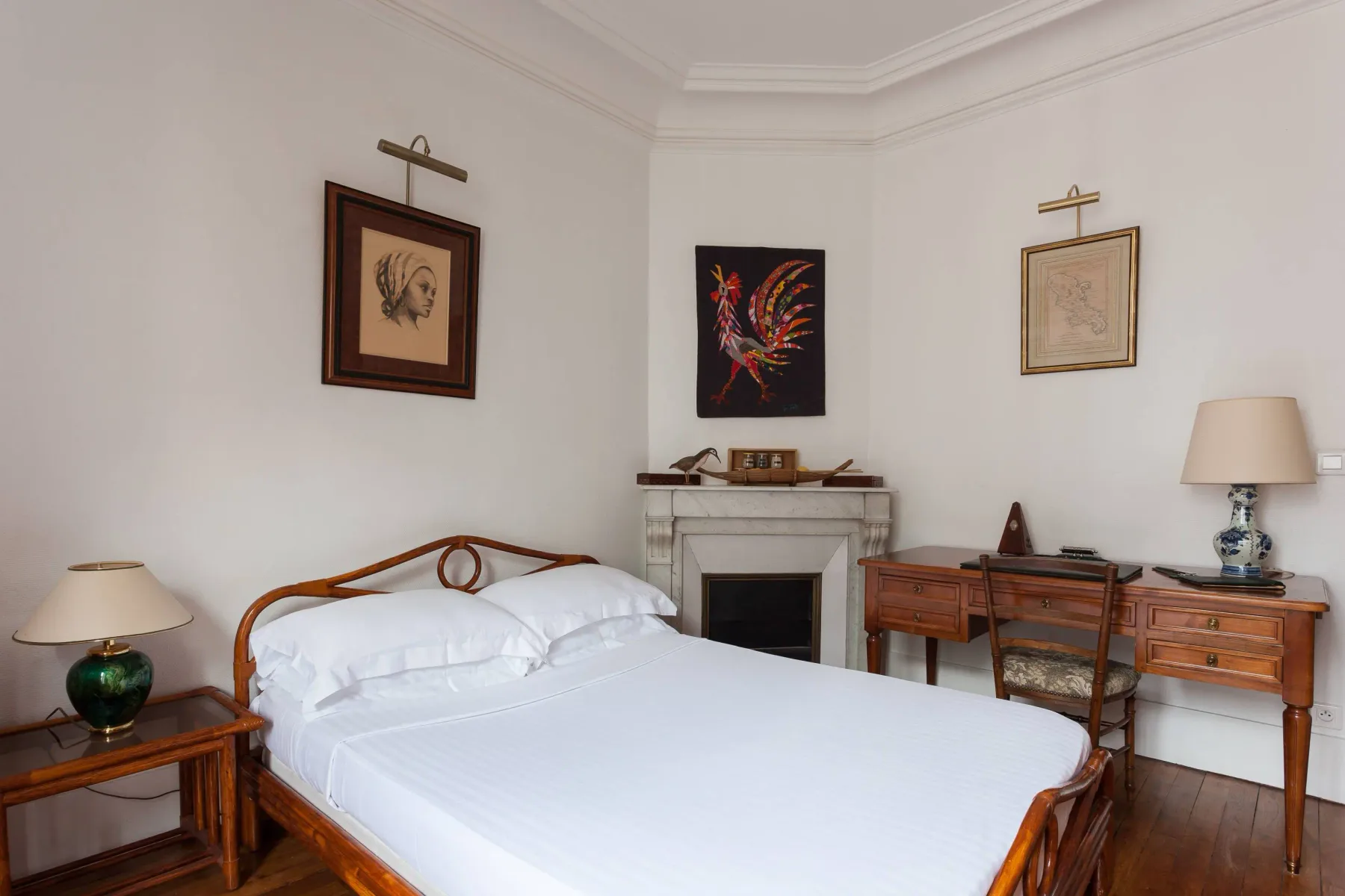A bedroom with a bed, fireplace, and wooden desk.