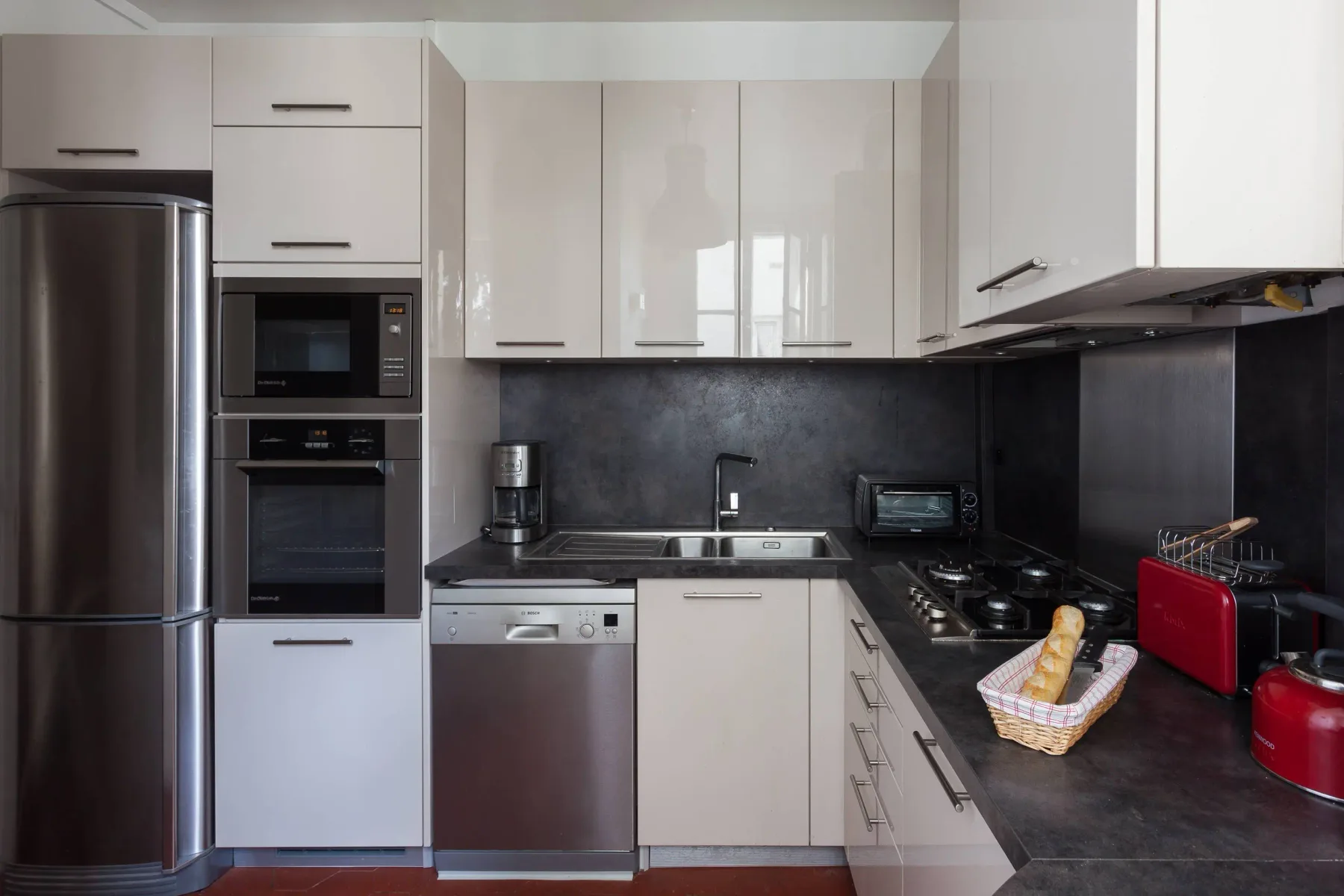 A modern kitchen with white cabinets and dark countertops.