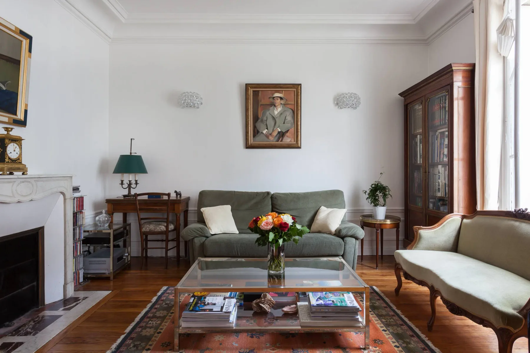 A living room with seating around a glass coffee table and flowers.