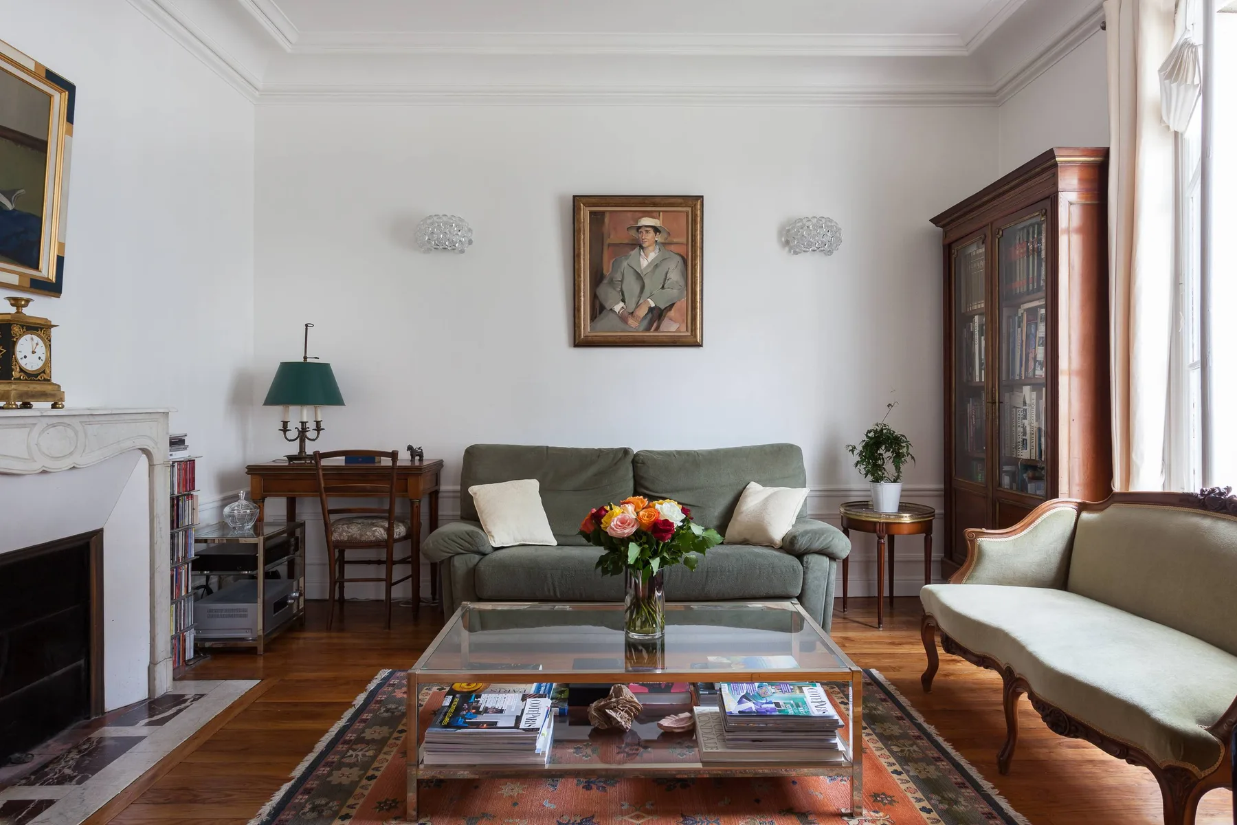 A living room with seating arranged around a glass coffee table and flowers.