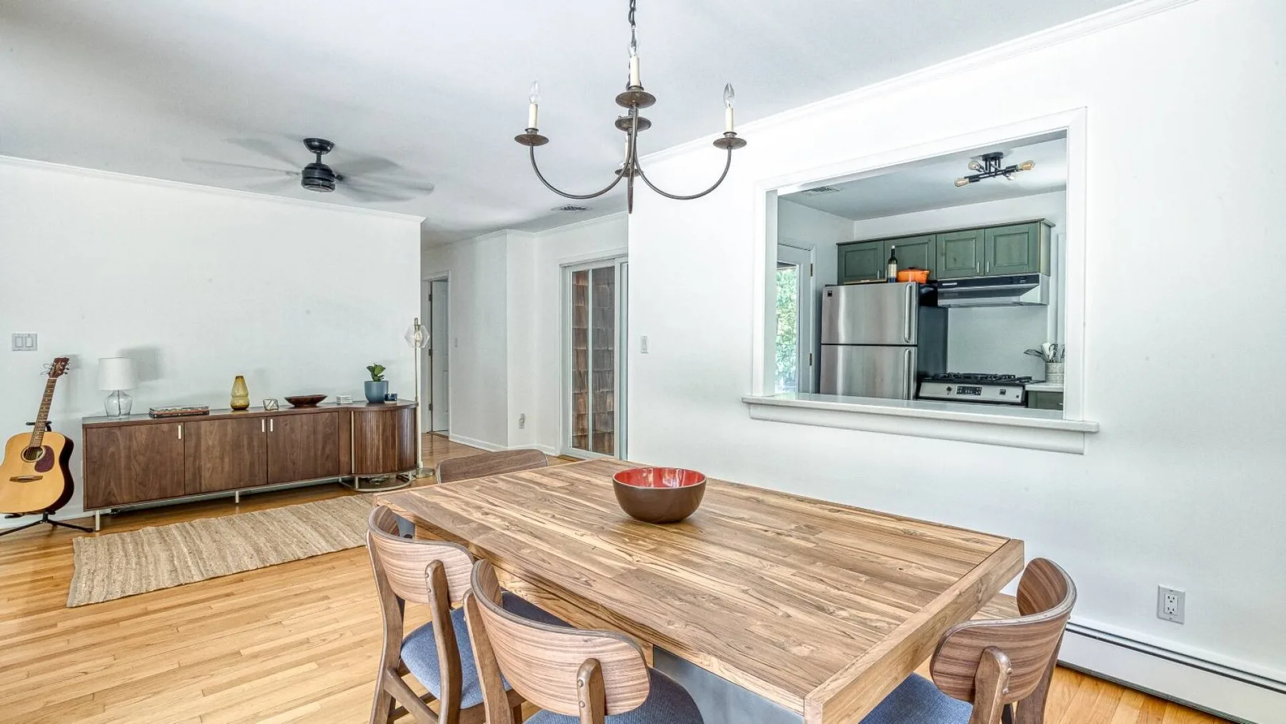 A dining area with a wooden table and an open view into the kitchen.