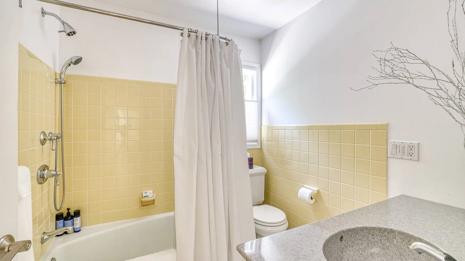 A bathroom with a bathtub, shower curtain, and sink.