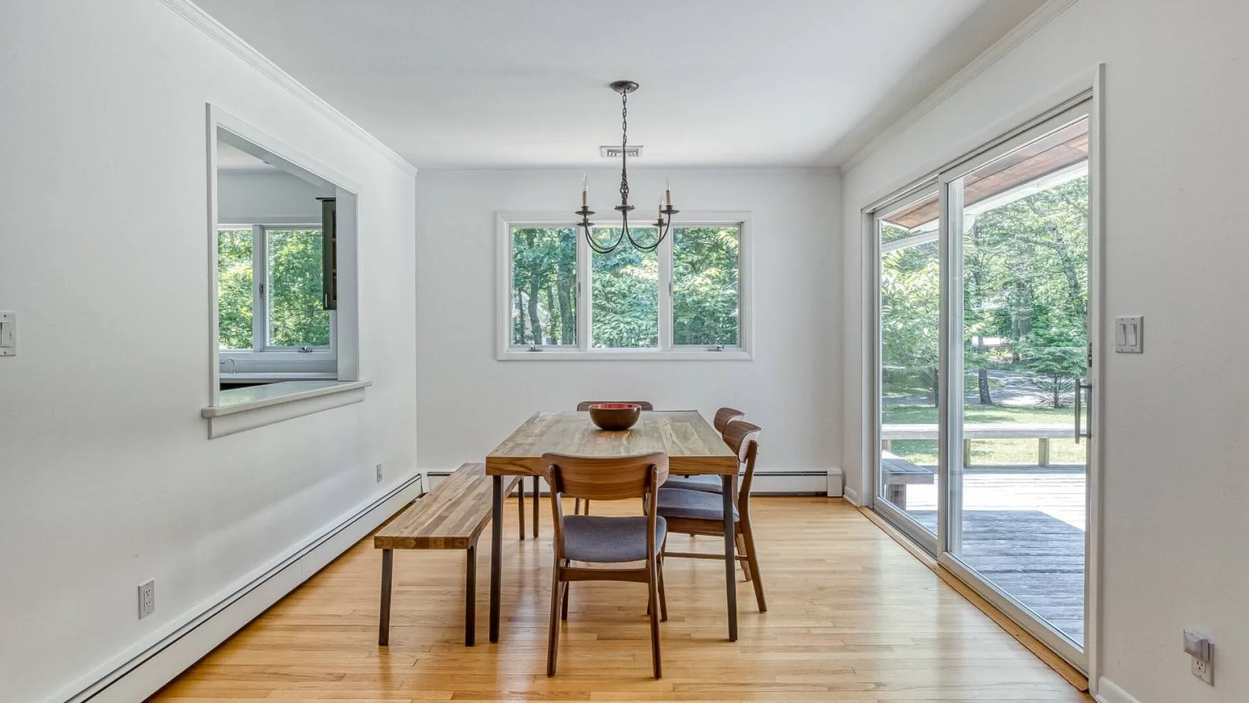 A bright dining room with a wooden table beside large glass doors.