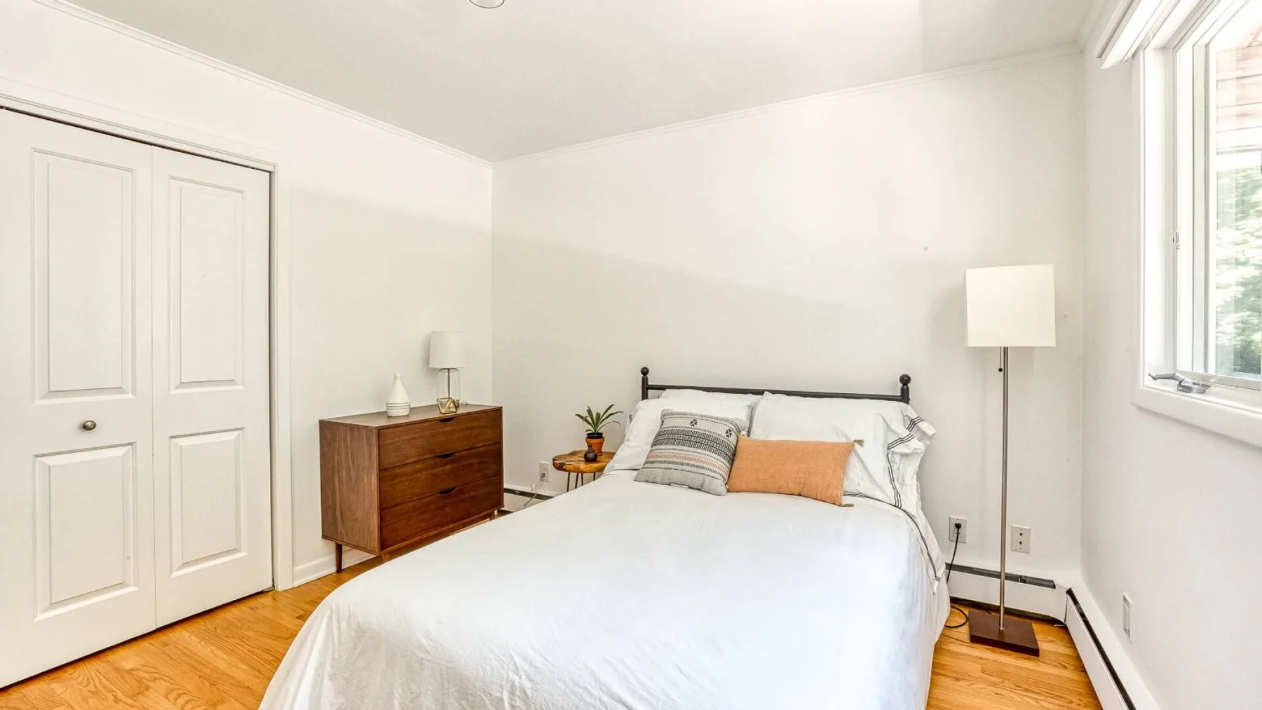A bright bedroom with a neatly made bed and a window.