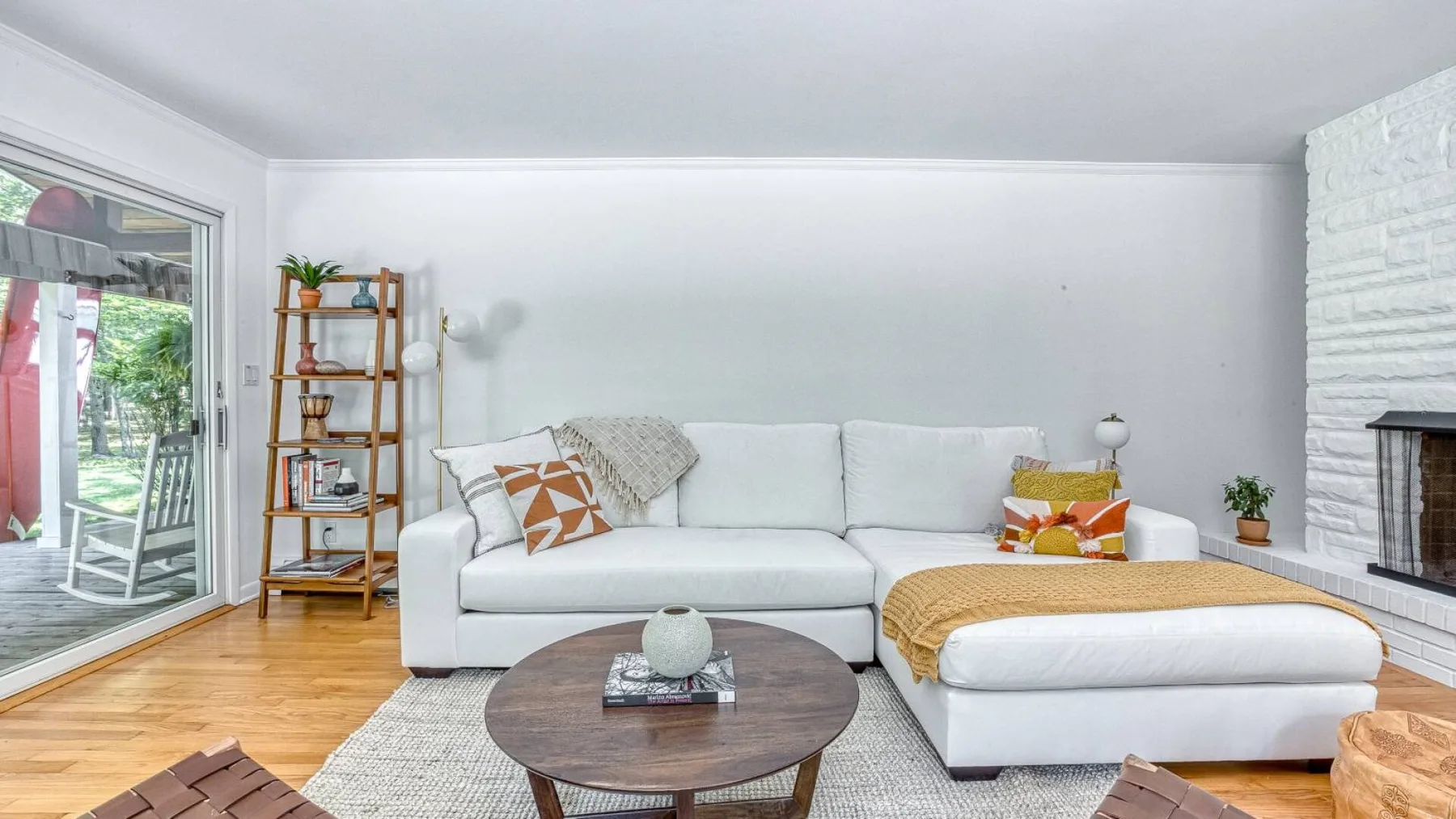 A bright living room with a white sectional sofa and a round coffee table.