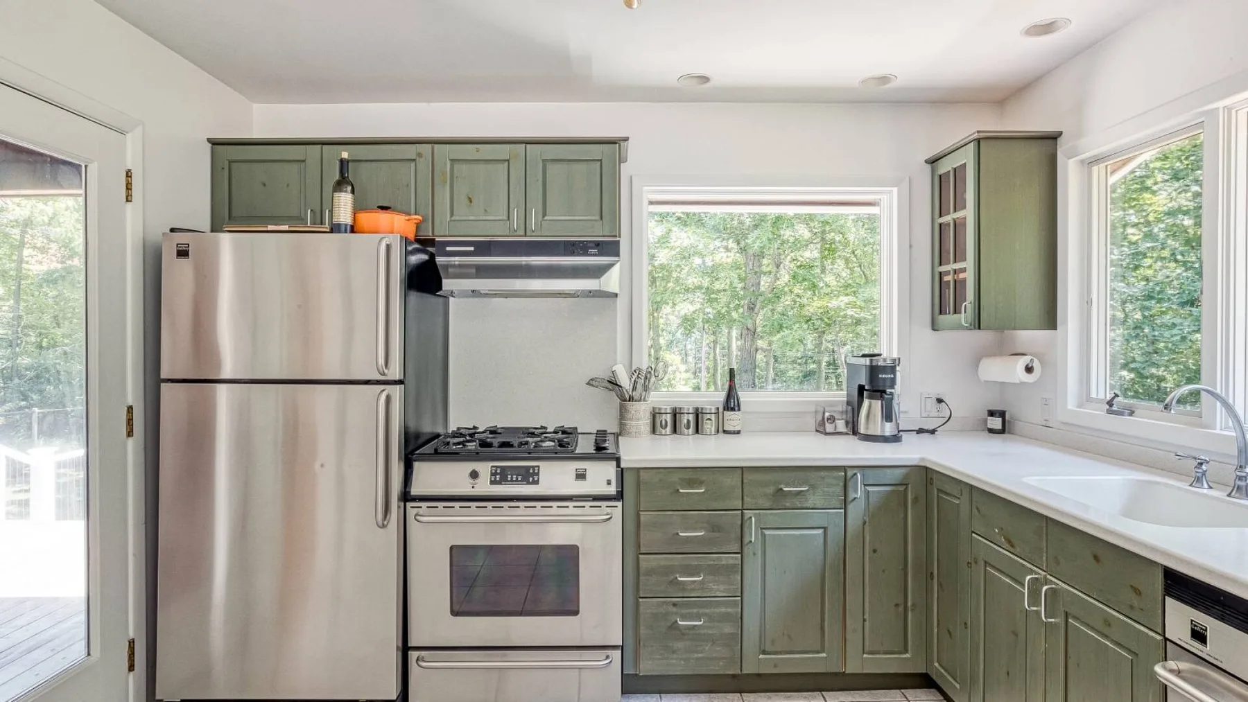 A kitchen with green cabinets, a refrigerator, and a stove.