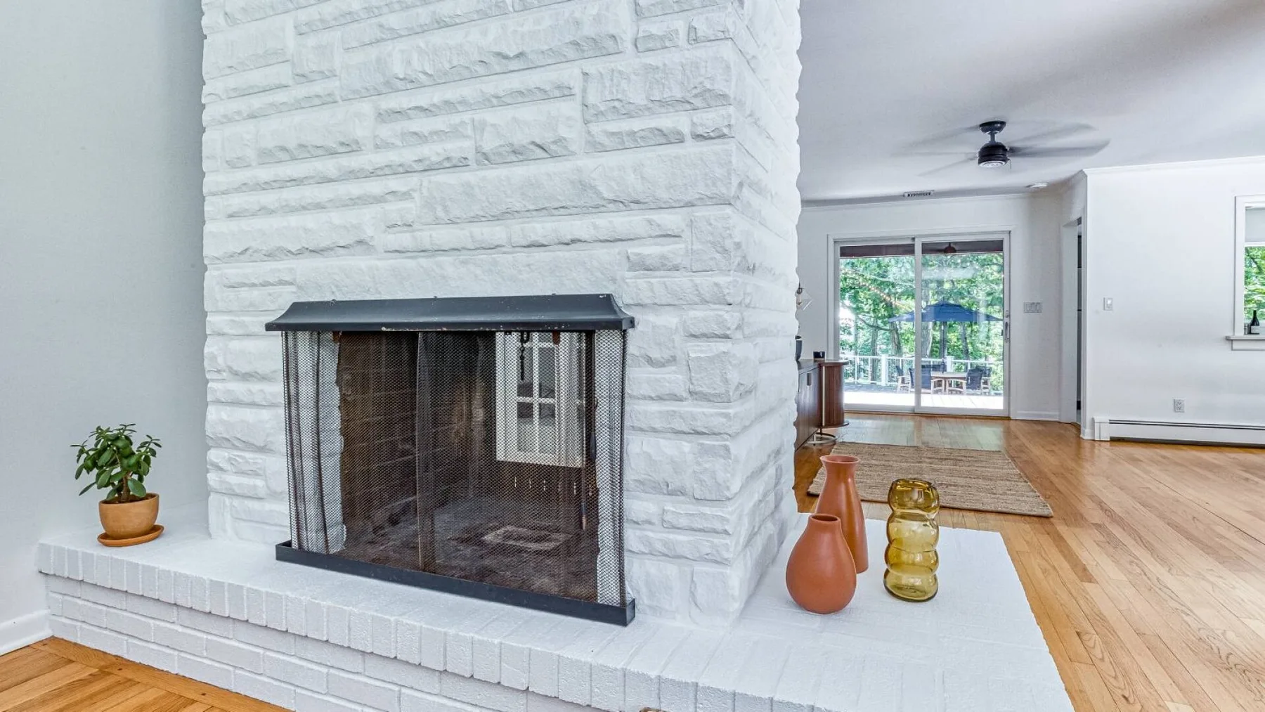 A bright living room with a white fireplace and glass doors opening to a patio.