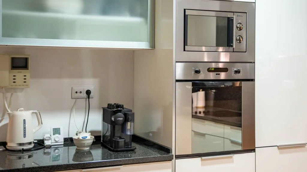 A modern kitchen counter with a kettle and built-in microwave and oven.