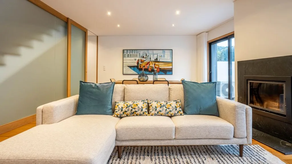 A living room with a sectional sofa, colorful cushions, and a fireplace.