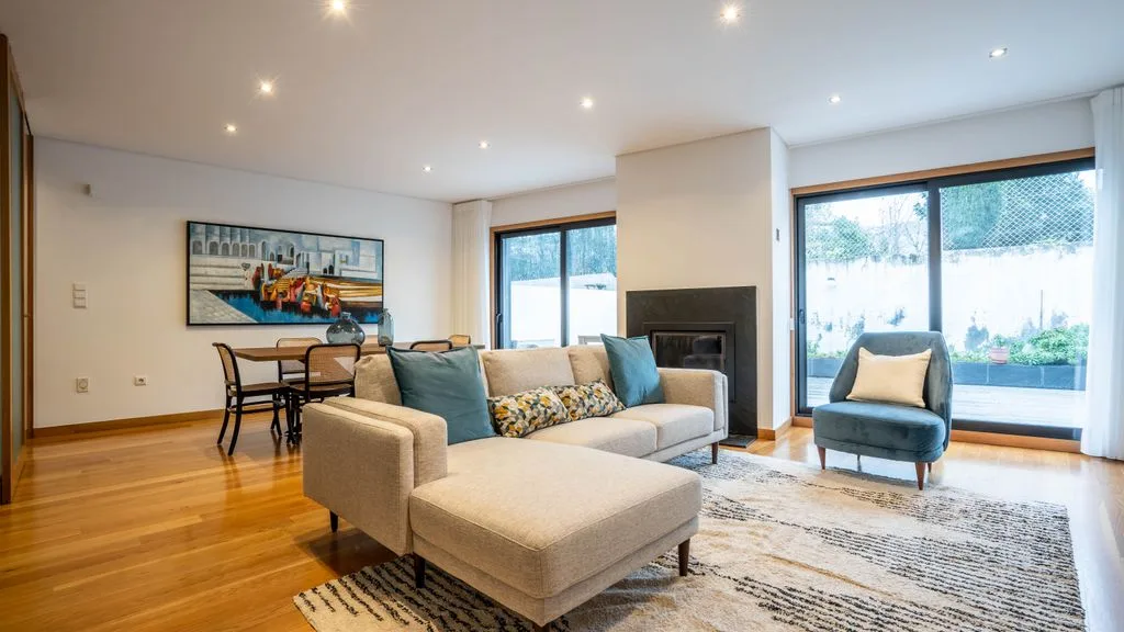 A bright living room with seating, a dining area, and large windows.