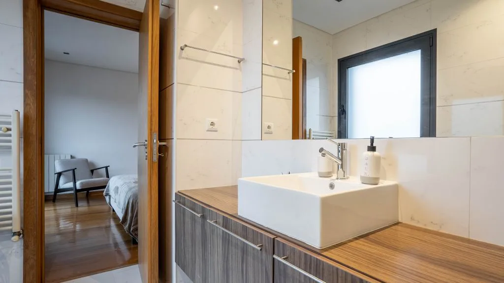 A bathroom with a sink and a doorway opening onto a bedroom.