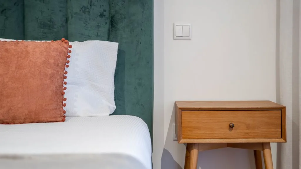 A bedroom with a bed and a wooden bedside table.