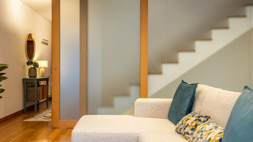 A living room with seating beside a staircase and wood-framed divider.
